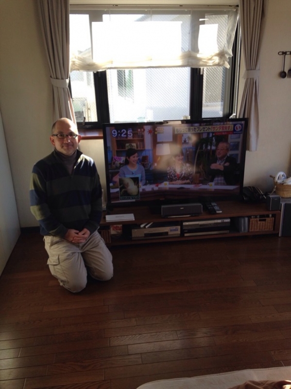 テレビ横で正座している男性