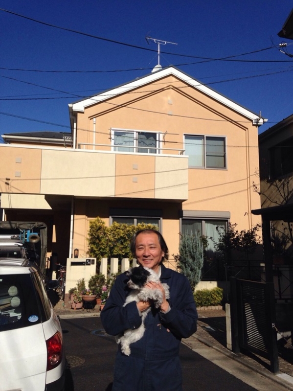 戸建住宅前で犬を抱えている男性