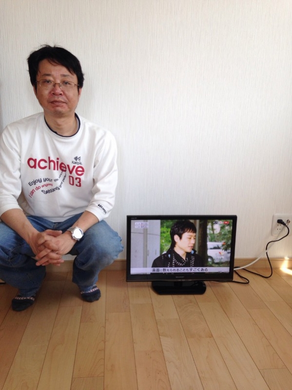 テレビ横でしゃがむ男性