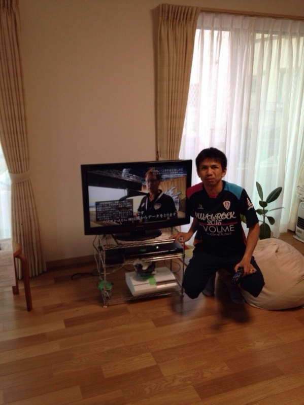 テレビ横でしゃがむ男性