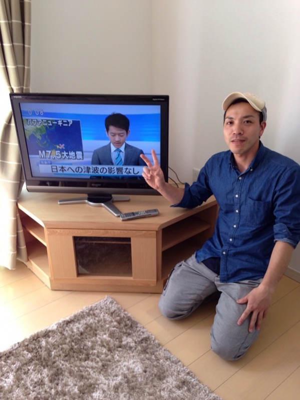 テレビ横でピースする男性
