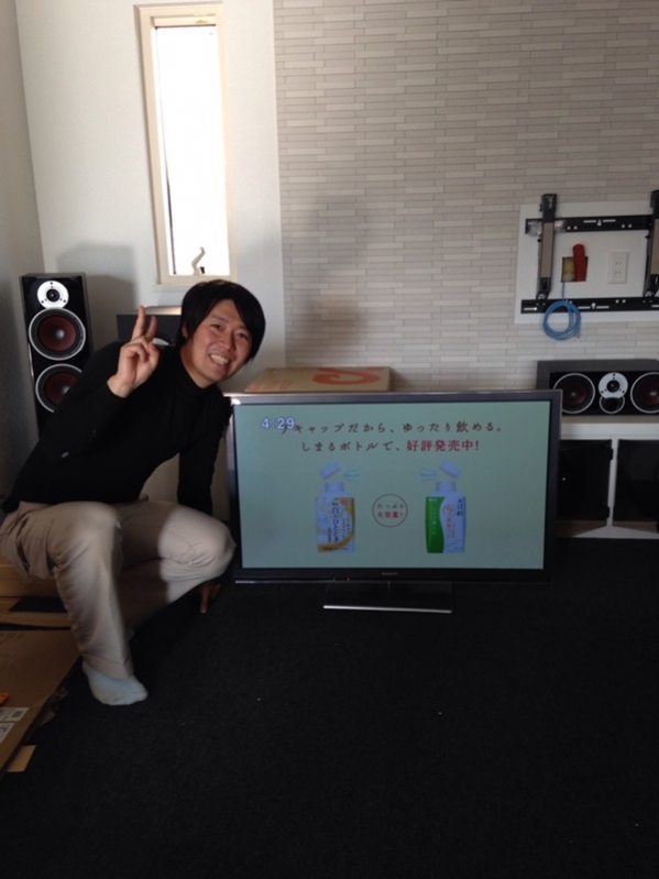 テレビ横でピースする男性