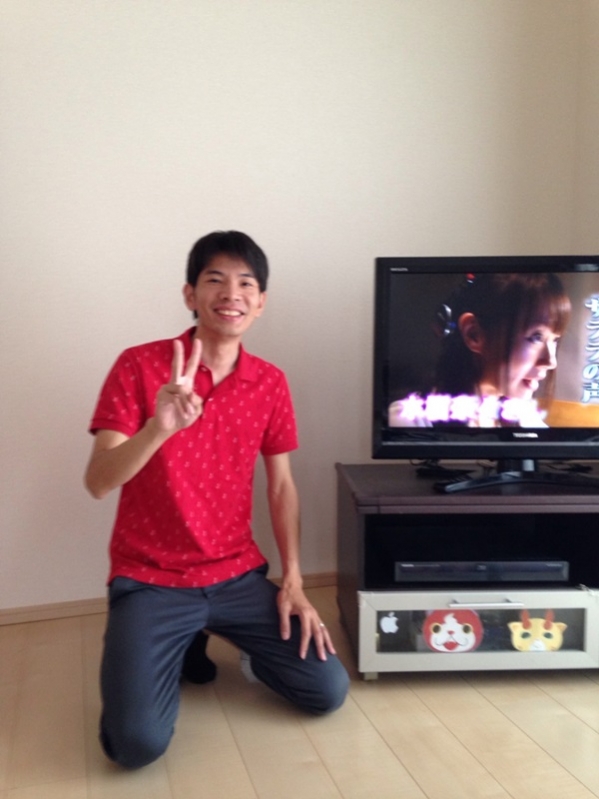 テレビ横でピースする男性