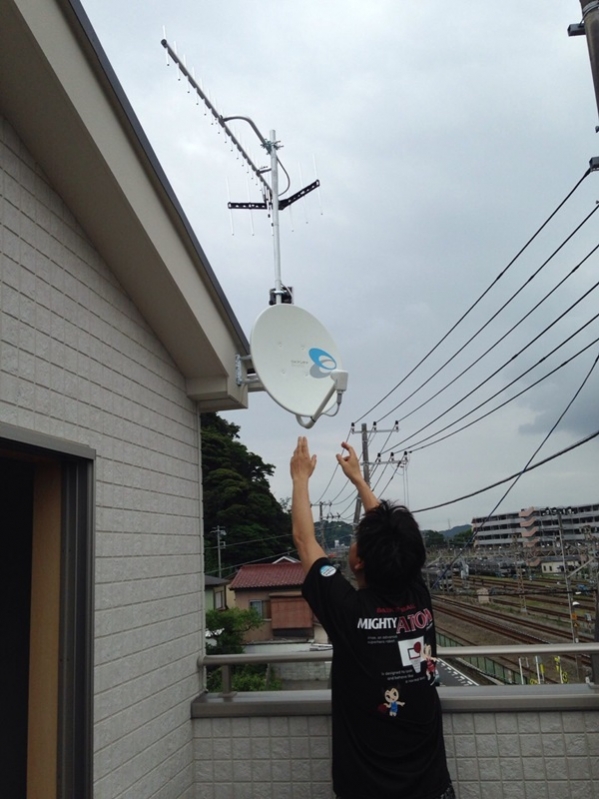 破風板のアンテナに手を伸ばす男性