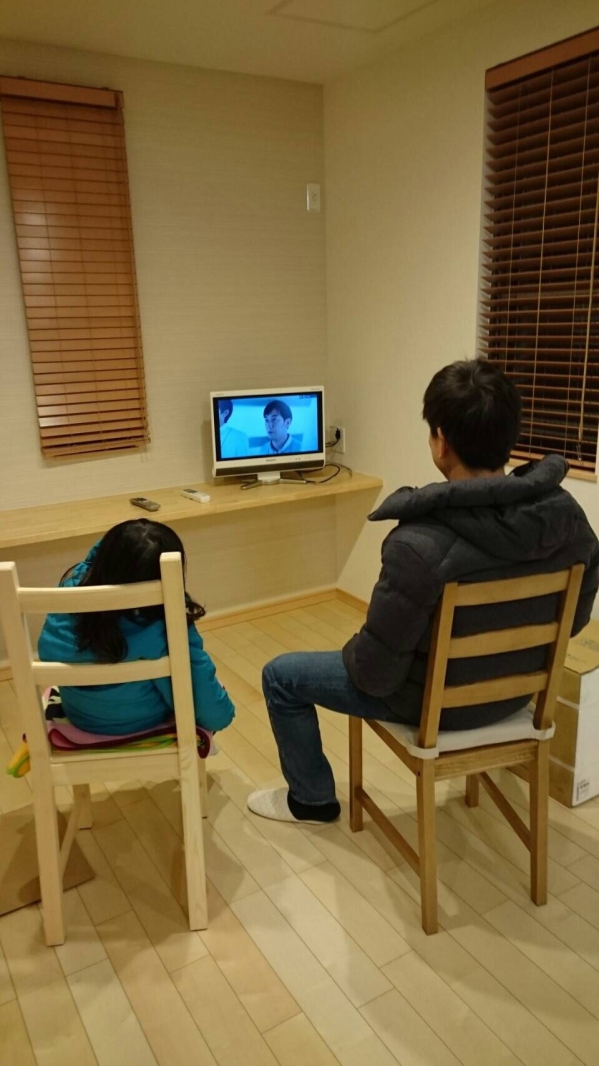 椅子に腰かけてテレビを見る親子
