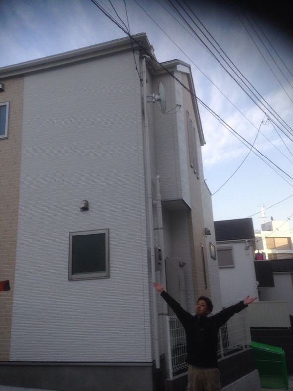 戸建住宅前で手を広げる男性