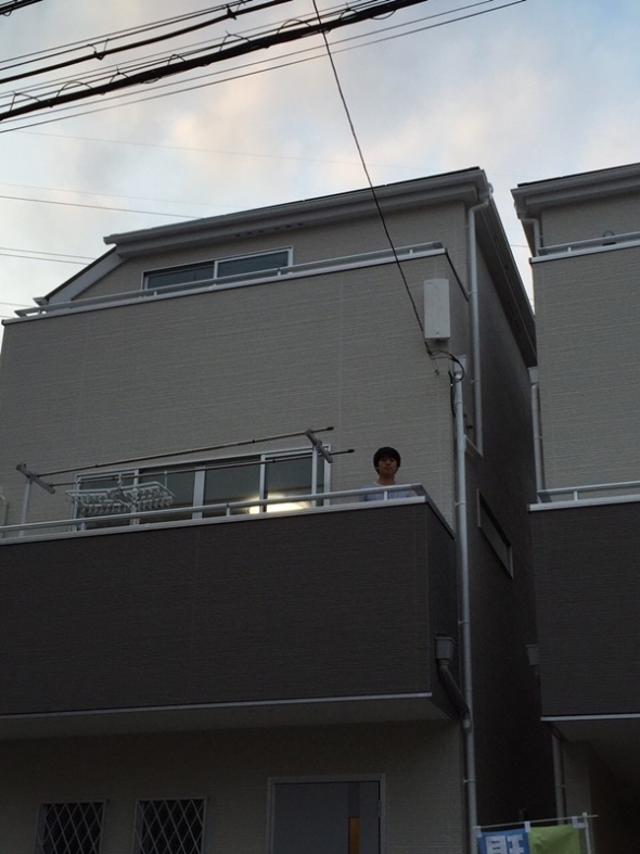 戸建住宅のベランダに立っている男性