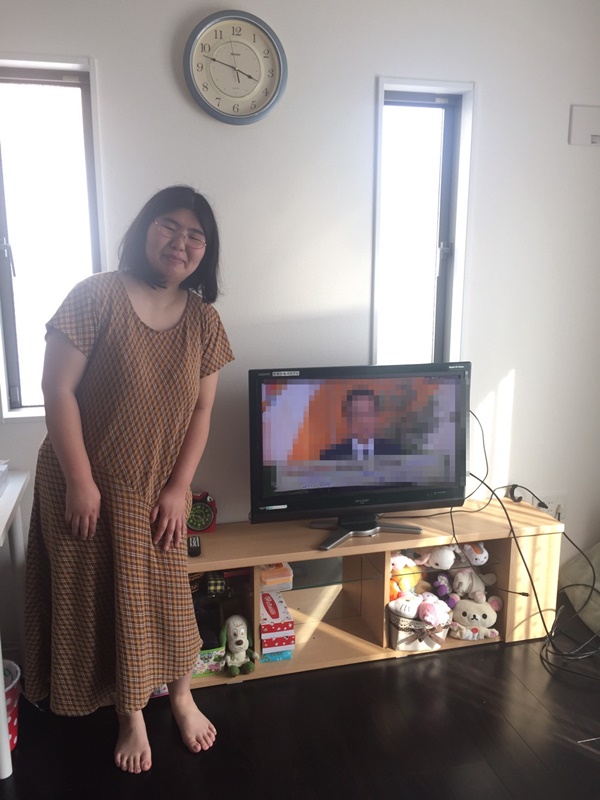 テレビ横に立つ女性