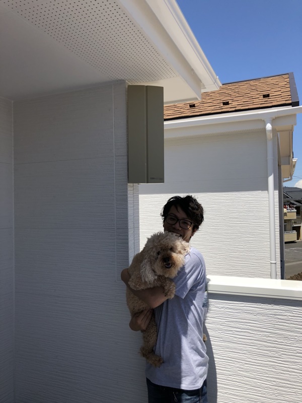 デザインアンテナ下で犬を抱えて撮影に応じる女性