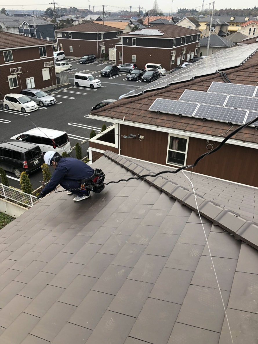 屋根上でアンテナ工事を行っている作業員