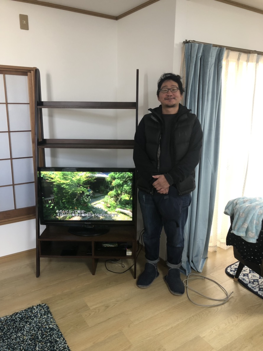 テレビの横に立つ男性