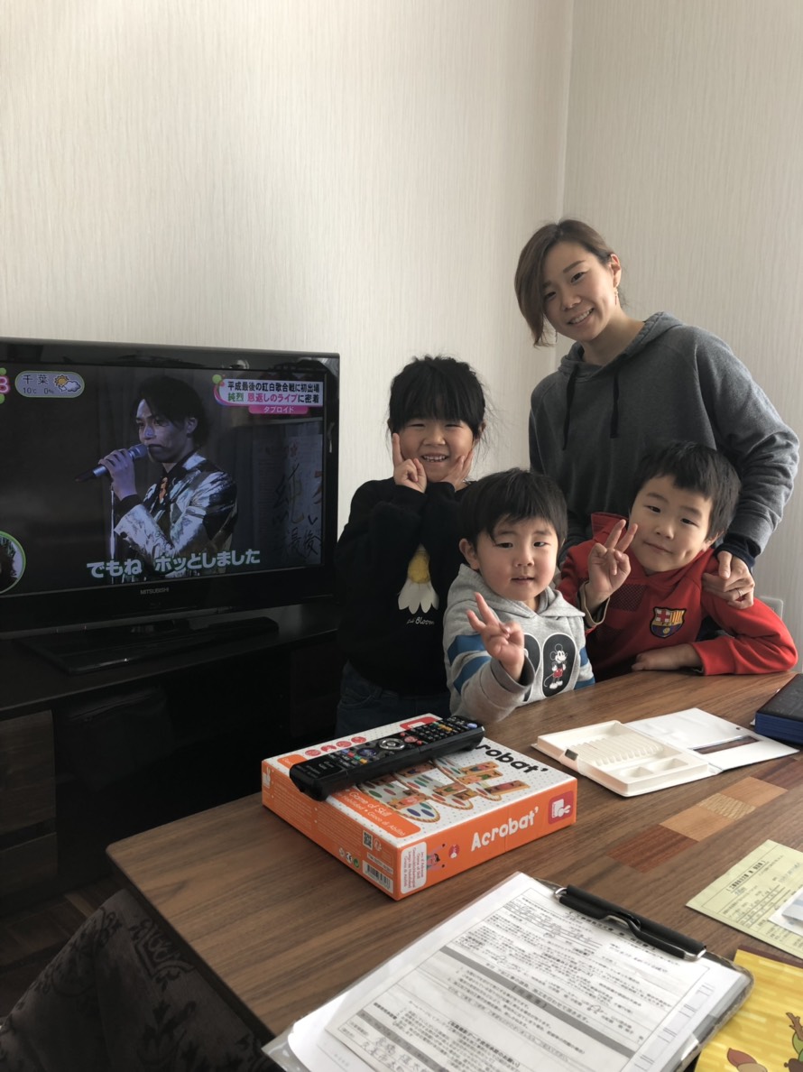 テレビ横の母親と3人の子供