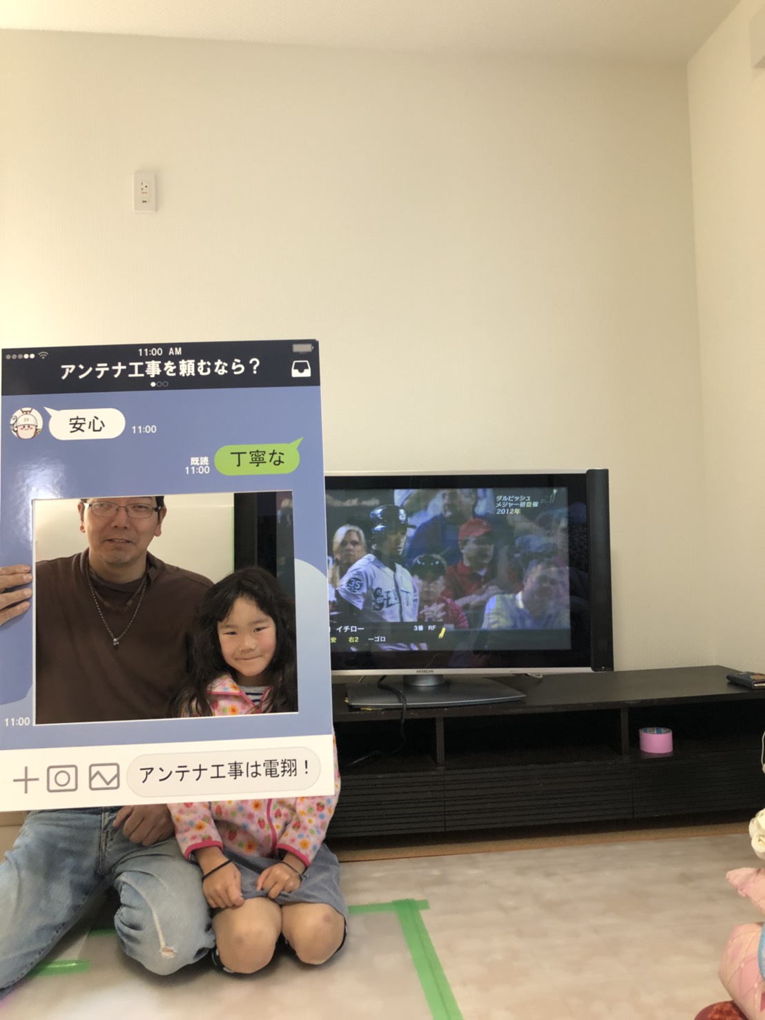 テレビ横でパネルを手にして撮影に応じる親子