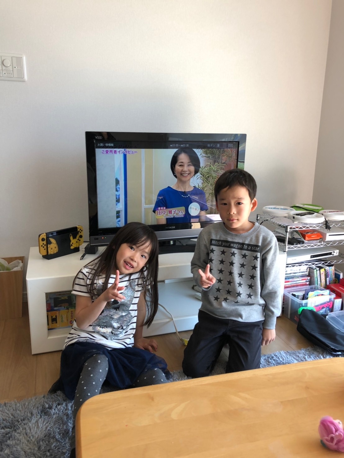 テレビ前でピースサインを作って撮影に応じる兄妹