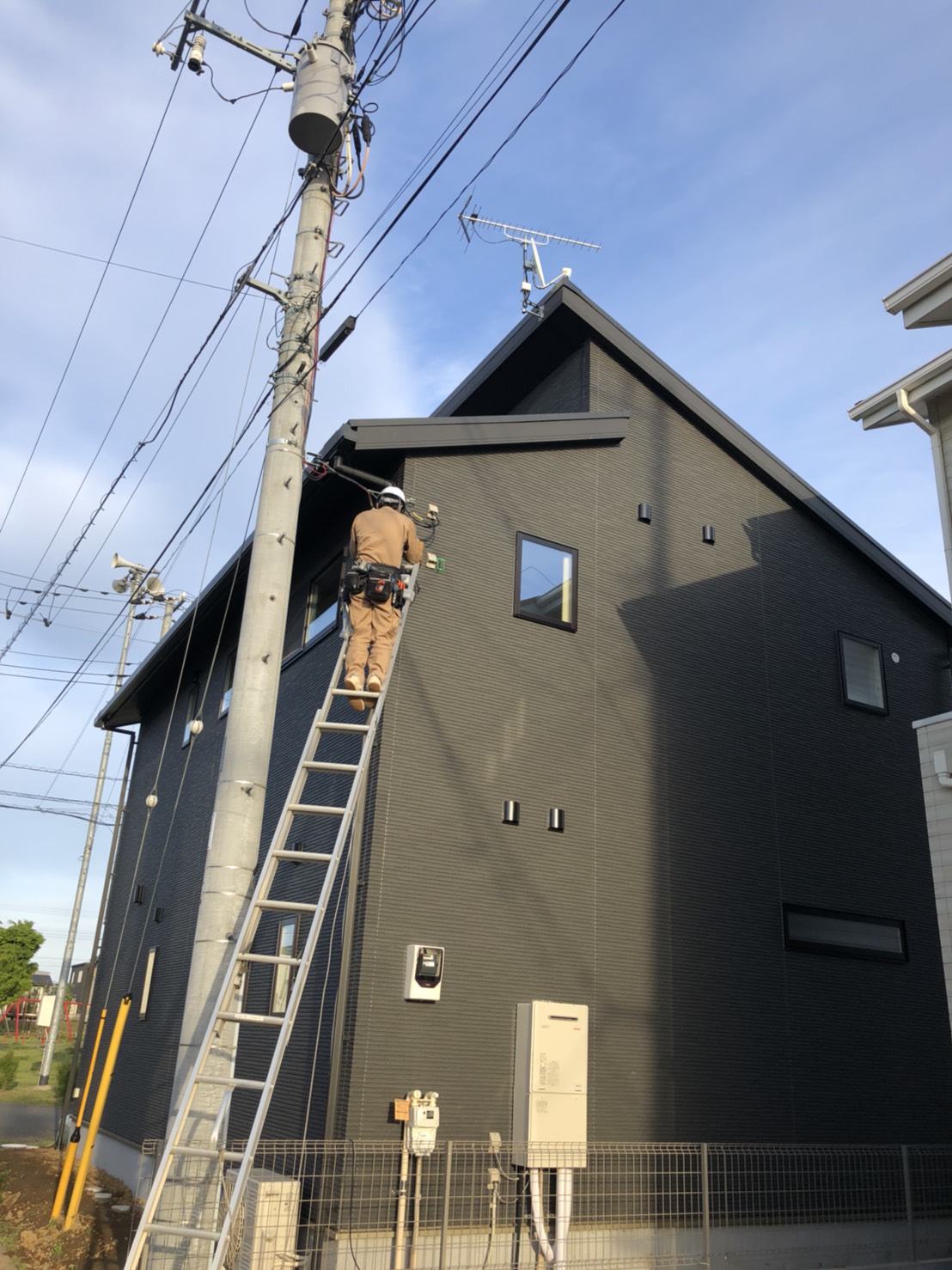 戸建住宅に梯子を立てかけ作業するスタッフ