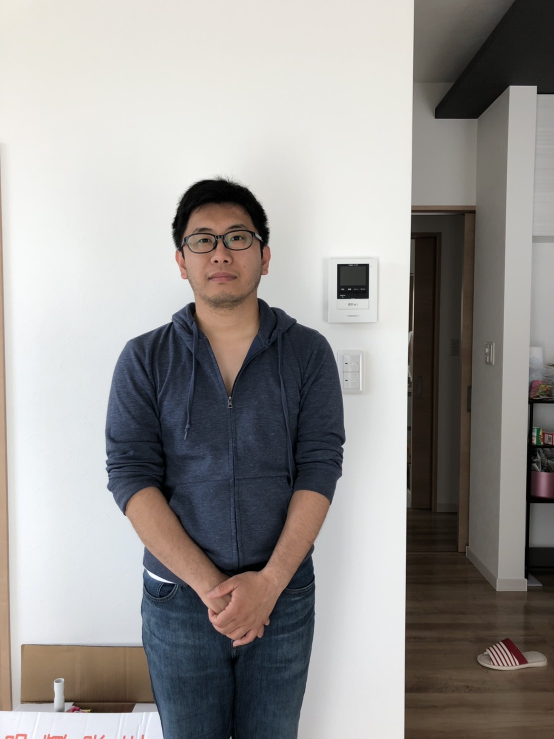 室内で手を前に組んで撮影に応じる男性