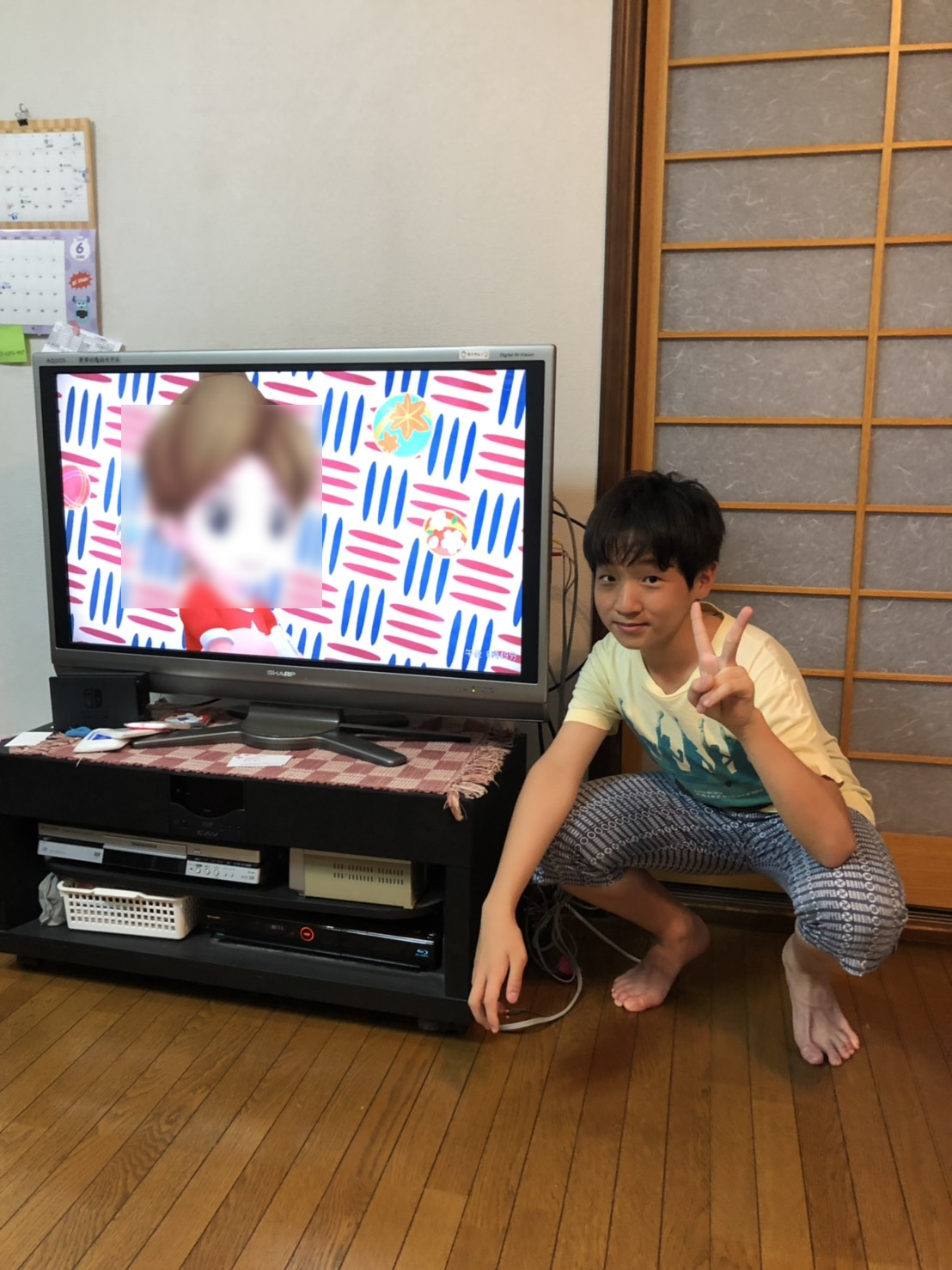 テレビ横でしゃがんでいる男性