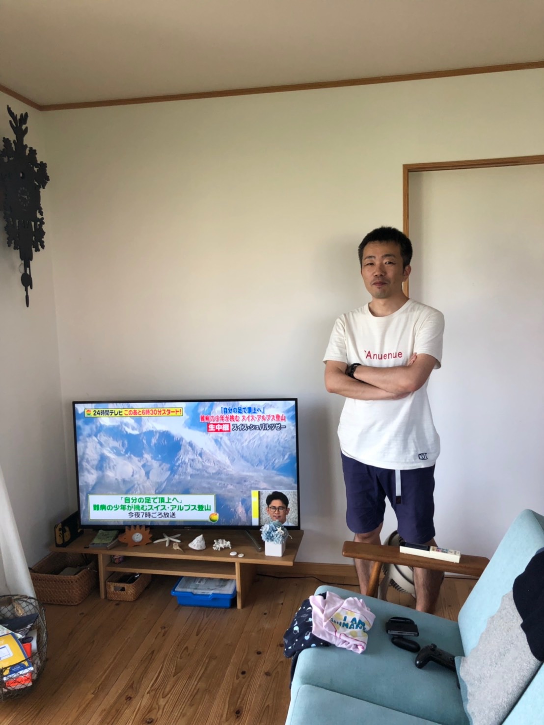 テレビ横で腕組みする男性