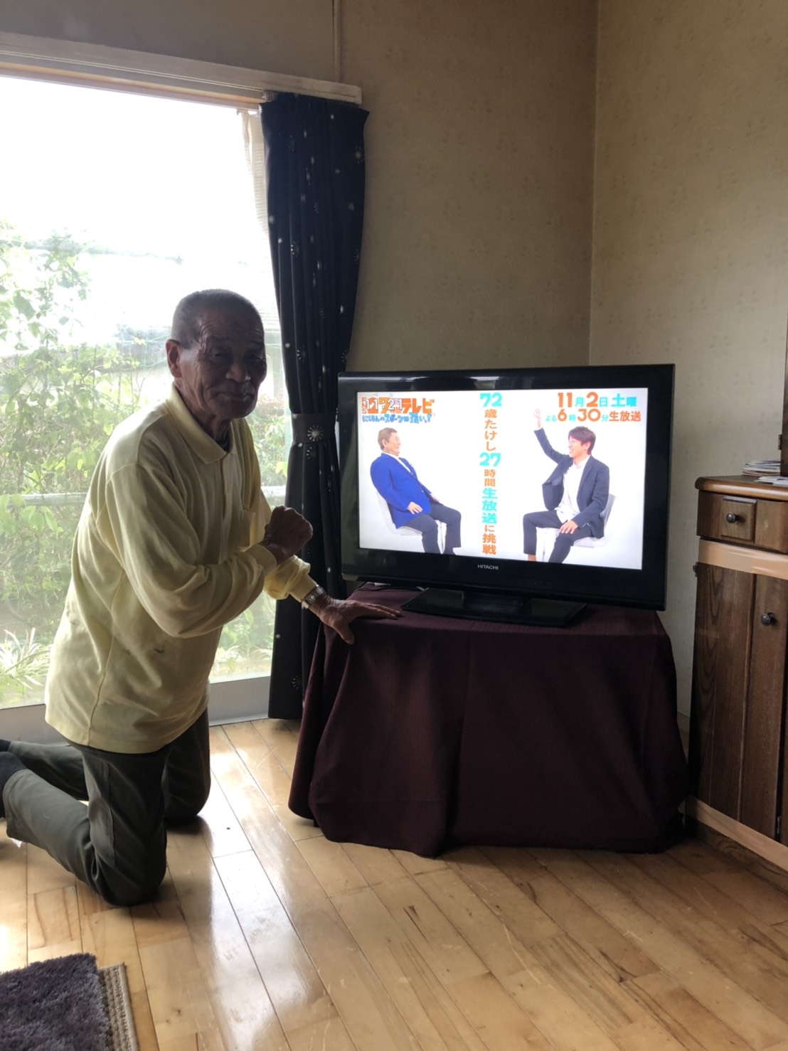 テレビ横で立膝姿の男性