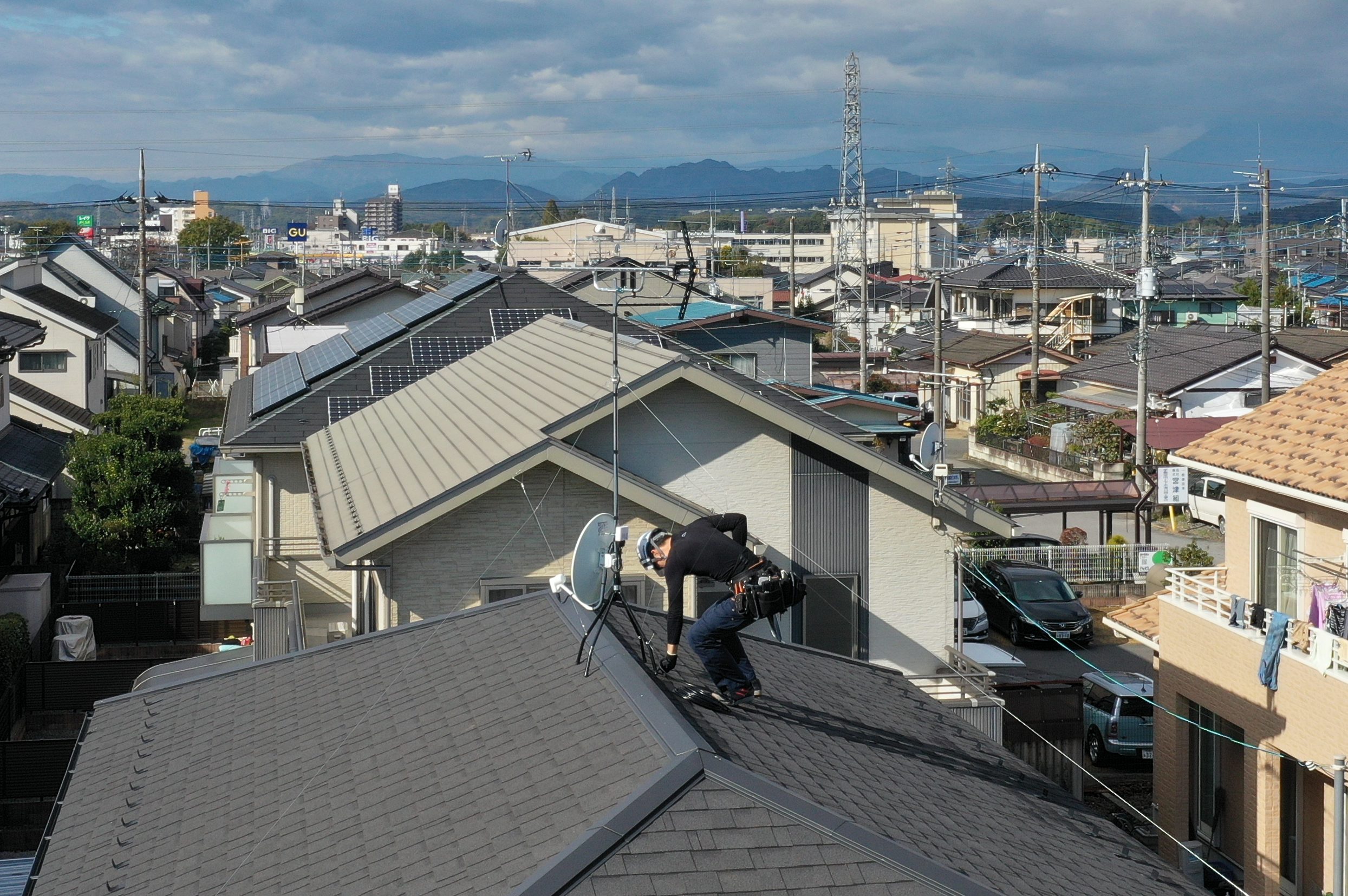 屋根上でアンテナ設置工事を行っている作業員