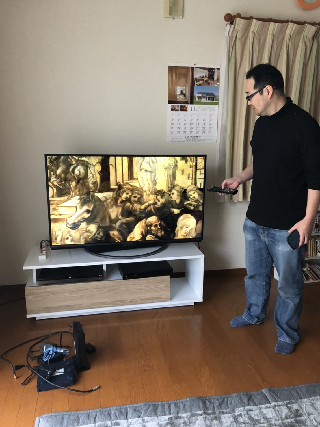 テレビ横でリモコンを操作する男性