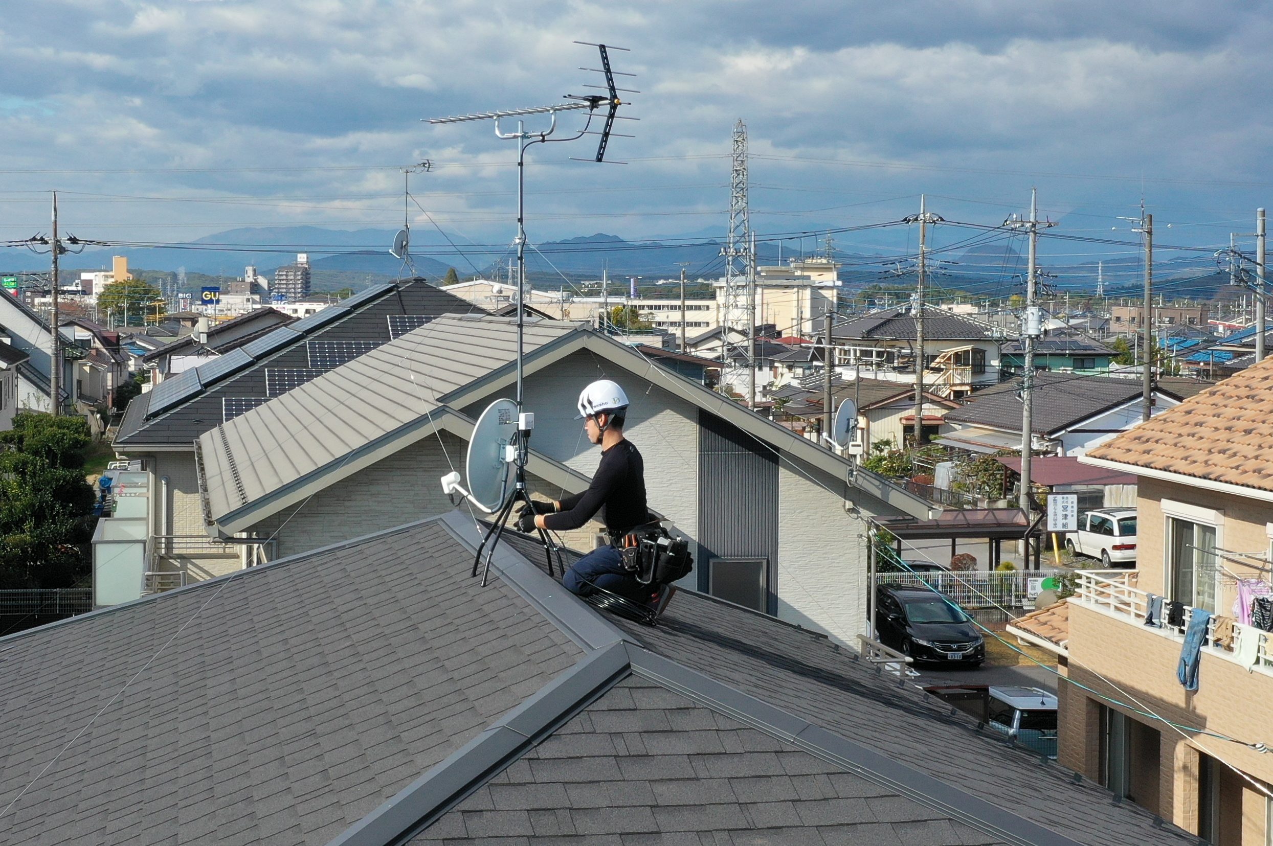 屋根上でアンテナ設置工事を行っている作業員