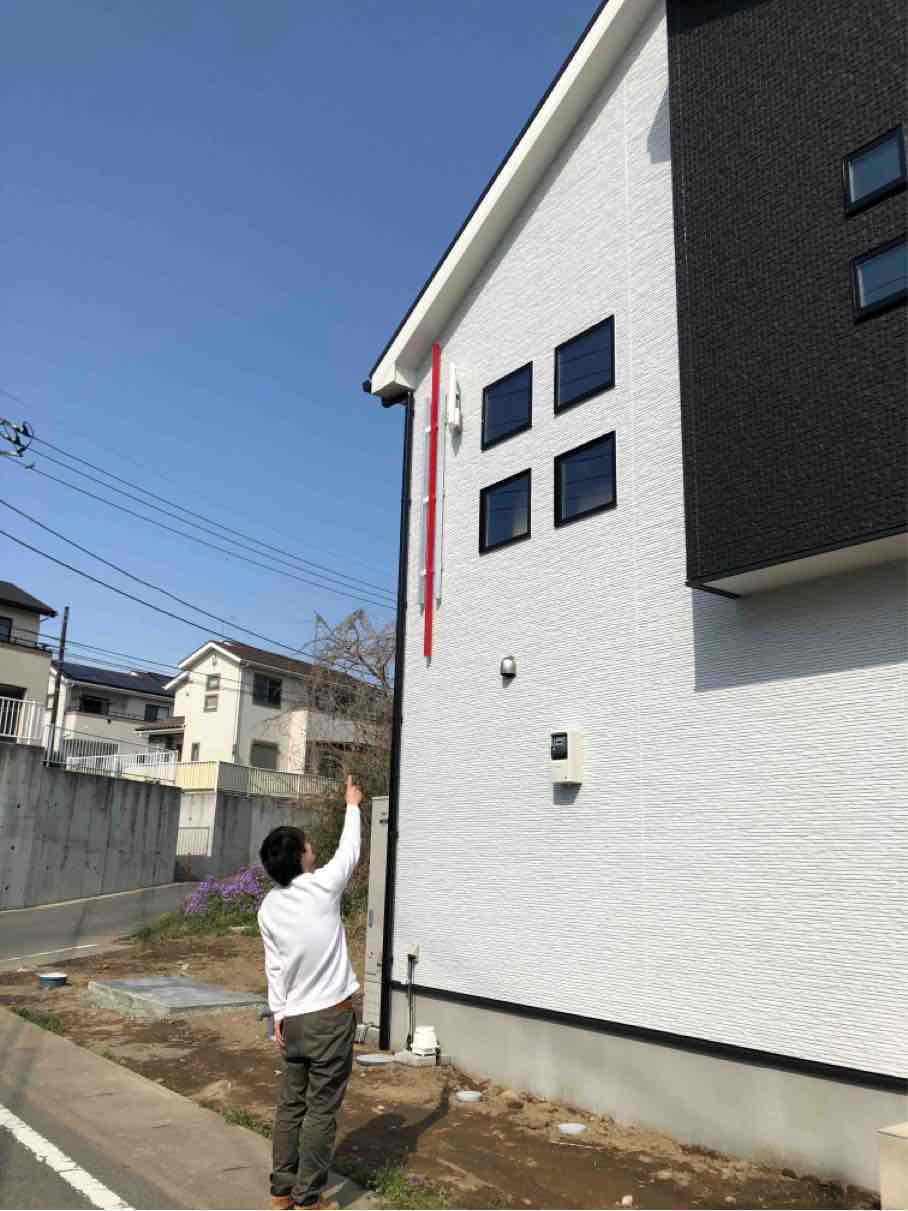 外壁に設置したアンテナを指さす男性