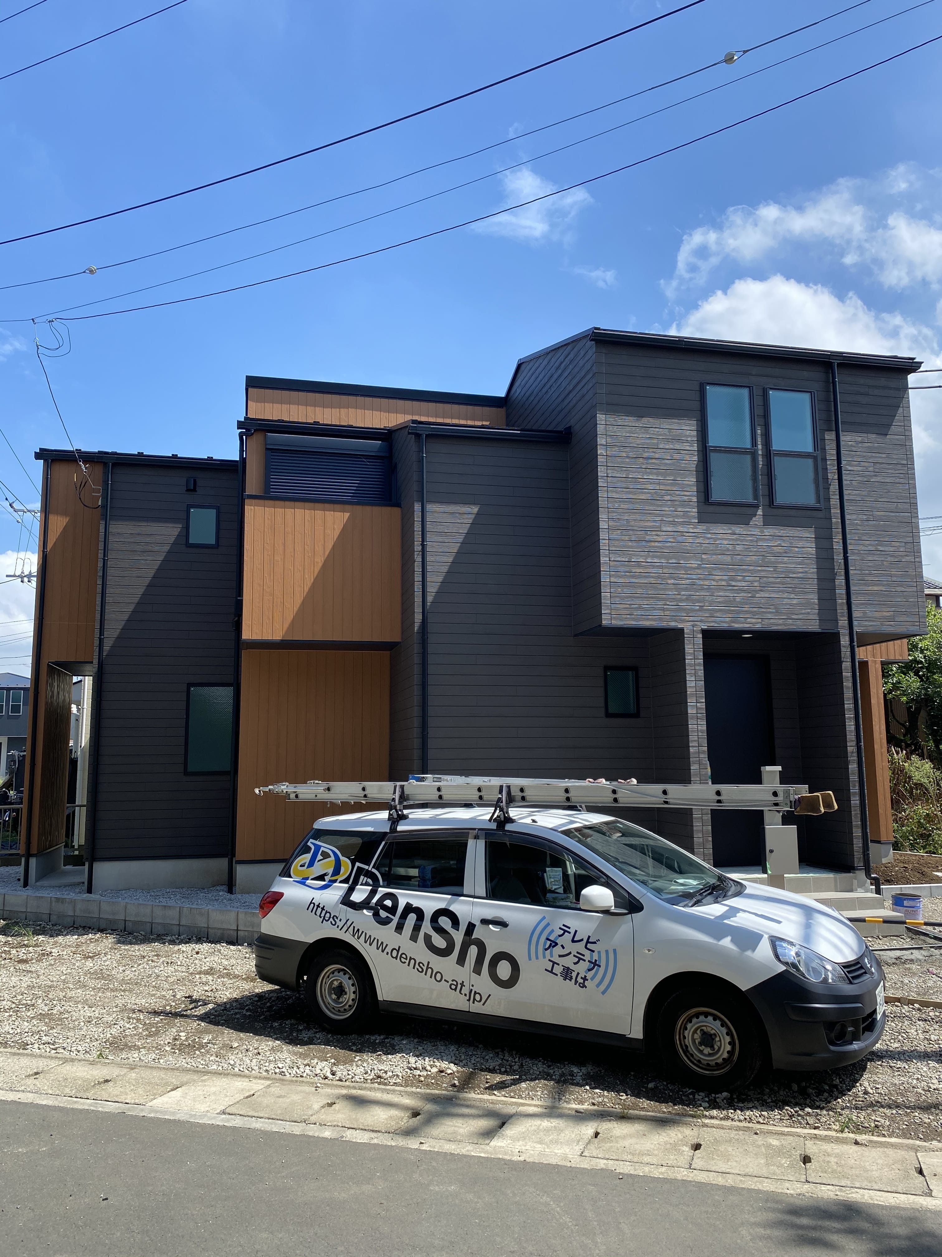 戸建住宅と敷地に停車した電翔ロゴカー